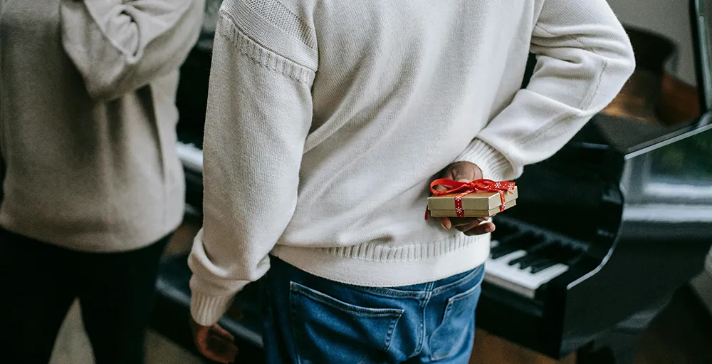 man hiding small gift behind back