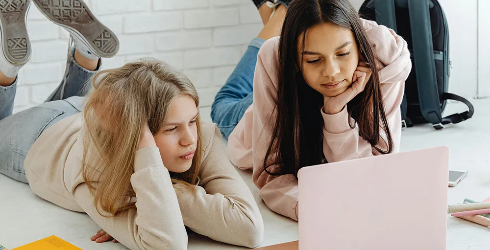 high school girls using pink laptop
