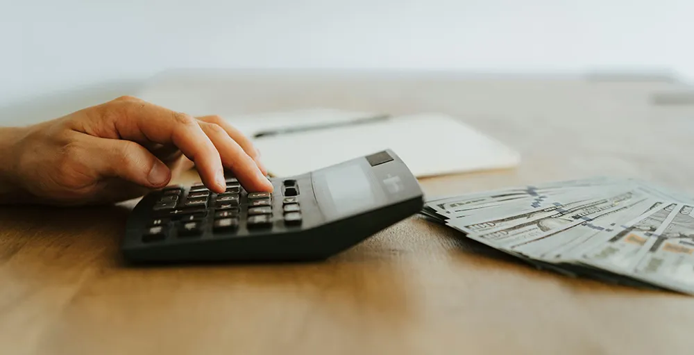 close-up photo of person using calculator to count money