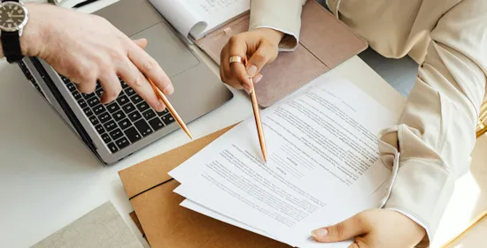 people pointing their pens on a printed paper