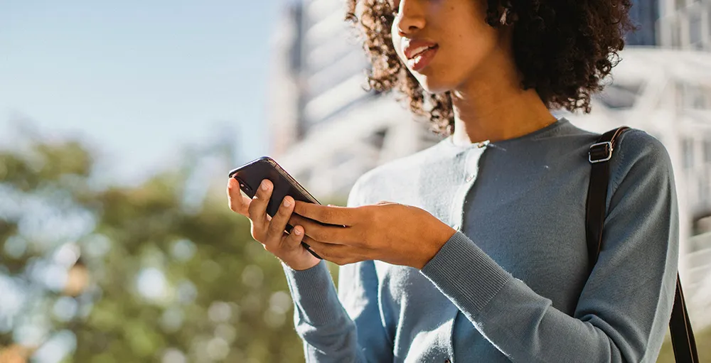 gen z woman in blue long sleeve shirt holding a cellphone