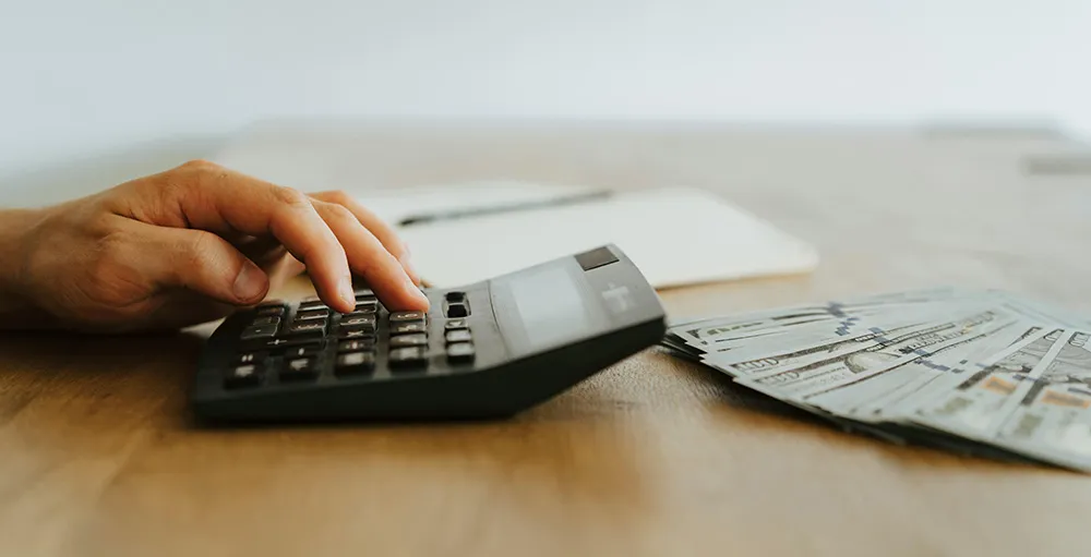 close-up of person with money using calculator