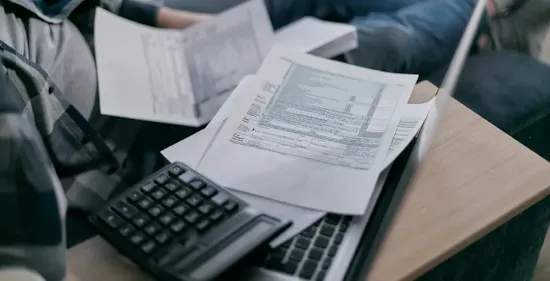 paper and calculator on top of laptop