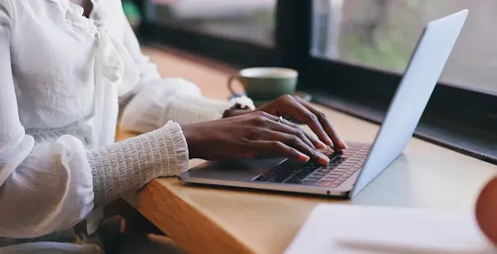 woman in coffee shop and typing on laptop