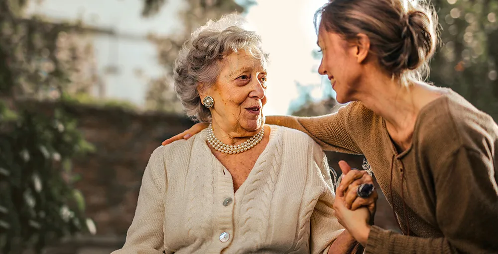 adult daughter greeting happy surprised senior mother in garden