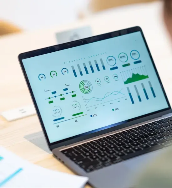 Laptop displaying a financial analysis dashboard with charts, graphs, and data visualizations in green and blue tones.