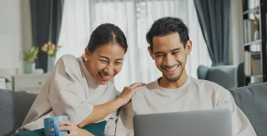 couple sitting on couch using laptop